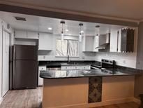Updated kitchen with stainless steel appliances, a breakfast bar, and modern lighting fixtures at 3275 Arville St # C, Las Vegas, NV 89102