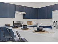 This kitchen features dark blue cabinets, stainless steel appliances, and a large white countertop island at 5692 Tinar St, Las Vegas, NV 89113