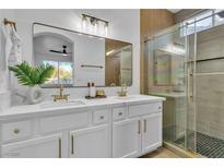 Modern bathroom featuring a double vanity with marble countertop and a sleek glass-enclosed shower at 10200 Wood Work Ln, Las Vegas, NV 89135