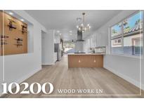 Bright, open kitchen boasts white cabinets, island, and modern light fixtures at 10200 Wood Work Ln, Las Vegas, NV 89135