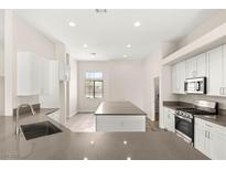Bright kitchen features white cabinets, stainless steel appliances, and a large gray quartz island at 6512 N Bruce St, North Las Vegas, NV 89086