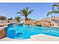 Inviting backyard pool with rock waterfall feature and lush tropical landscaping at 6638 Dazzling Heights Ln, Las Vegas, NV 89110