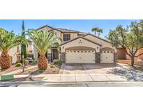 Charming two-story home featuring a three-car garage and meticulously landscaped front yard with palm trees at 664 Blue Crystal Creek Rd, Henderson, NV 89002