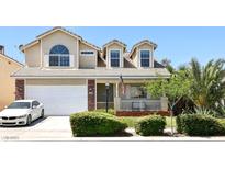 Inviting two-story home featuring a well-manicured lawn, lush landscaping, and attached two-car garage at 7729 Natures Song St, Las Vegas, NV 89131