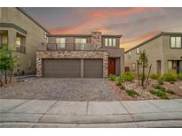 Inviting two-story home featuring a stone facade, three-car garage, balcony and landscaped front yard at 10189 Magnolia Creek St, Las Vegas, NV 89141