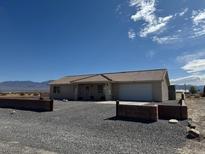 Single story house with a gravel driveway and a two car garage under a clear blue sky at 1321 Yosemite Ave, Pahrump, NV 89048