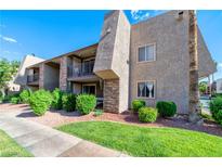 Charming condo building with stucco siding, green lawns, shrubbery, balconies, and mature palm trees at 4390 Sandy River Dr # 1, Las Vegas, NV 89103