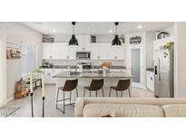 Bright kitchen features white cabinets, granite countertops, stainless steel appliances, and an island with barstool seating at 8316 Gold River Ct, Las Vegas, NV 89113