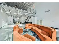 Modern living room featuring concrete floors, a cozy orange sofa set, and an open floor plan at 5077 Thunder River Cir, Las Vegas, NV 89148