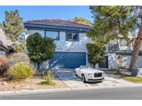 Two-story home boasts a tile roof, tidy landscaping, and a blue garage door, with a luxury car parked in the driveway at 916 Vegas Valley Dr, Las Vegas, NV 89109