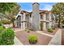 Inviting condo featuring a stucco facade, a decorative chimney, and an external staircase at 1575 W Warm Springs Rd # 413, Henderson, NV 89014