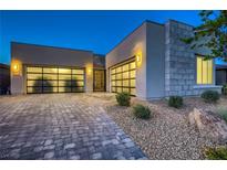 Contemporary home featuring a stylish three-car garage, stone accents, and desert landscaping at 2910 Raywood Ash Dr, Las Vegas, NV 89138