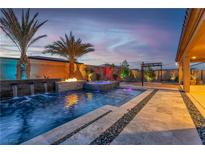 Backyard pool with waterfalls, fire pit, colorful lights and lush palm trees at dusk at 9091 Becket Ranch Ct, Las Vegas, NV 89113