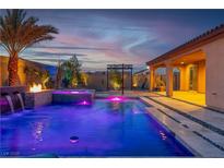Beautiful pool with water features and a fire pit offering a relaxing outdoor oasis with vibrant lighting at 9091 Becket Ranch Ct, Las Vegas, NV 89113