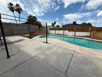 Backyard swimming pool with a concrete patio under a metal pergola surrounded by block and wood fencing at 4186 Toronto Cir, Las Vegas, NV 89121