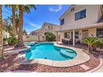 Inviting backyard pool with lush palm trees and a covered patio, perfect for outdoor relaxation and entertaining at 8942 Galena Crossing St, Las Vegas, NV 89123
