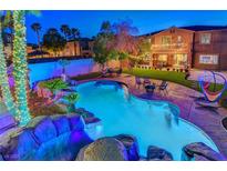 An illuminated backyard oasis with a sparkling pool, rock waterfall, and festive string lights, perfect for evening relaxation at 112 Kava Kava St, Henderson, NV 89015