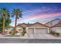 Charming single-story home featuring a two-car garage, desert landscaping, and vibrant sunset skies at 1552 Livingston Dr, Henderson, NV 89012