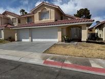 Inviting two-story home featuring a red-tiled roof, arched entryway, and a spacious two-car garage at 7620 Tortola Bay Ln, Las Vegas, NV 89128