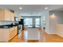 Bright kitchen features stainless appliances, wood floors and light cabinets with island at 9050 W Tropicana Ave # 1053, Las Vegas, NV 89147