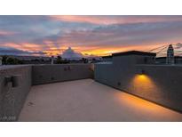 Open rooftop patio with lights offering a stunning view of the colorful sunset over distant mountains at 9050 W Tropicana Ave # 1053, Las Vegas, NV 89147