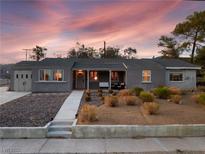 Charming single-story home featuring a well-maintained front yard with a cozy front porch seating area at 650 Arizona St, Boulder City, NV 89005