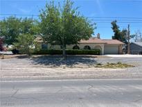Charming single-story home featuring a tile roof, well-maintained landscaping, and an attached two car garage at 881 E Calvada Blvd, Pahrump, NV 89048
