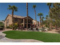 Beautiful backyard with pool, lawn, and palm trees; perfect for outdoor entertaining at 9012 Alpine Peaks Ave, Las Vegas, NV 89147
