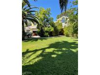 Landscaped front yard with a well-maintained lawn and mature trees, offering curb appeal at 1385 Ringe Ln, Las Vegas, NV 89110
