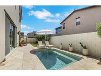 Inviting backyard featuring a pristine pool, lounge chairs, a shade umbrella and desert landscaping at 513 Monarch Ridge Ct, North Las Vegas, NV 89084