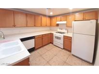 A functional kitchen includes wood cabinets, white countertops, and appliances on neutral tile floors at 9580 W Reno Ave # 183, Las Vegas, NV 89148