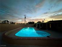 Sparkling pool with landscape and illuminated lights at dusk at 1615 Palora Ave, Las Vegas, NV 89169