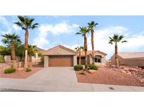 Charming single-story home featuring a two-car garage and desert landscaping with mature palm trees at 3157 Faiss Dr, Las Vegas, NV 89134