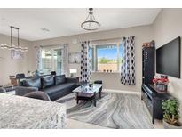 Cozy living room with a black leather sofa, area rug, and view to the backyard at 12426 Oregon Cherry Ave, Las Vegas, NV 89138