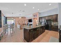 Open concept kitchen features a center island, stainless steel appliances, and seamlessly connects to the dining and living areas at 2104 Leatherbridge Ct, North Las Vegas, NV 89081