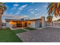A backyard has an outdoor dining area with string lights, gravel and artificial turf at 5208 Overland Ave, Las Vegas, NV 89107