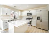 Bright kitchen featuring an island, stainless steel appliances, white cabinets and quartz countertops at 5345 Tustin Hills St, North Las Vegas, NV 89081