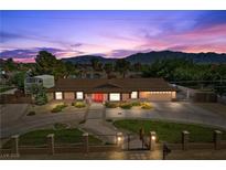 Charming single-story home featuring a well-manicured lawn, mature trees, and mountain views at 7350 W Rome Blvd, Las Vegas, NV 89131