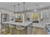 Bright kitchen boasts white cabinets, stainless appliances, large island with seating, and modern pendant lighting at 8848 Rainbow Ridge Dr, Las Vegas, NV 89117