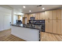 Open kitchen with black countertops, wood floors, stainless appliances, and custom cabinets at 1032 Hassett Ave, Las Vegas, NV 89104