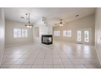 Spacious living room featuring vaulted ceilings, a fireplace, tile floors, and multiple windows providing natural light at 1563 Cattle Ranch Pl, Henderson, NV 89002