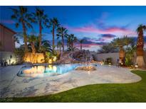 Backyard oasis featuring a gorgeous pool with a waterfall and palm trees set against a stunning twilight sky at 3924 Diamond Ridge St, Las Vegas, NV 89129
