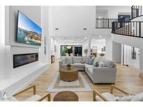 Bright, open living room features modern fireplace, entertainment center, and elegant staircase to the second floor at 5225 Villa Dante Ave, Las Vegas, NV 89141