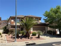 Two-story home with a well-manicured front yard featuring desert landscaping and mature palm trees at 96 Saint Johns Wood Ave, Henderson, NV 89002