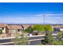Neighborhood street view showcasing lush greenery, sidewalks and a glimpse of the city skyline in the background at 4012 Owlshead Mountain St, Las Vegas, NV 89129