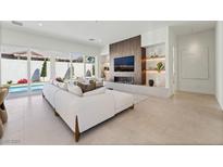 Bright living room featuring modern fireplace, built-in shelving, and access to the backyard pool at 10528 Garden Light Dr, Las Vegas, NV 89135