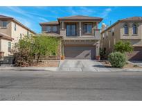 Two-story home featuring a balcony, neutral stucco, stone accents, finished two-car garage and manicured landscaping at 4992 W Moberly Ave, Las Vegas, NV 89139