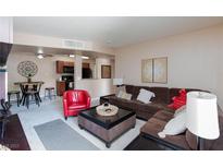 Inviting living room featuring a comfortable brown sectional sofa and bright red accent chair at 2120 Ramrod Ave # 513, Henderson, NV 89014