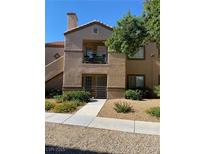 Beige two-story home featuring a balcony, landscaped yard, and tile roof under a bright blue sky at 3450 Erva St # 167, Las Vegas, NV 89117