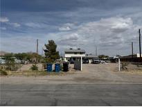 Exterior view of a two-story home with a large, dirt front yard and several parked vehicles at 664 Spring Rd, Indian Springs, NV 89018